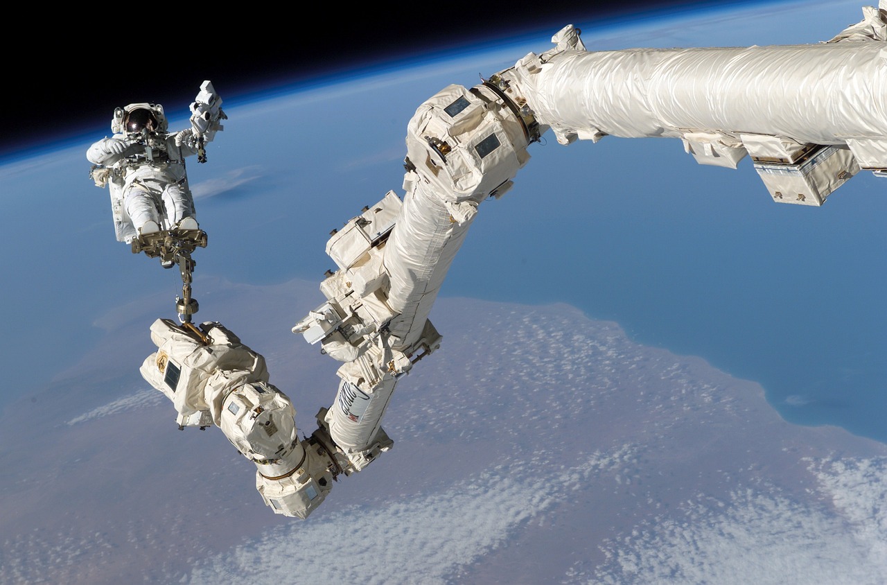 Astronaut in a white spacesuit performing a spacewalk outside a space station.