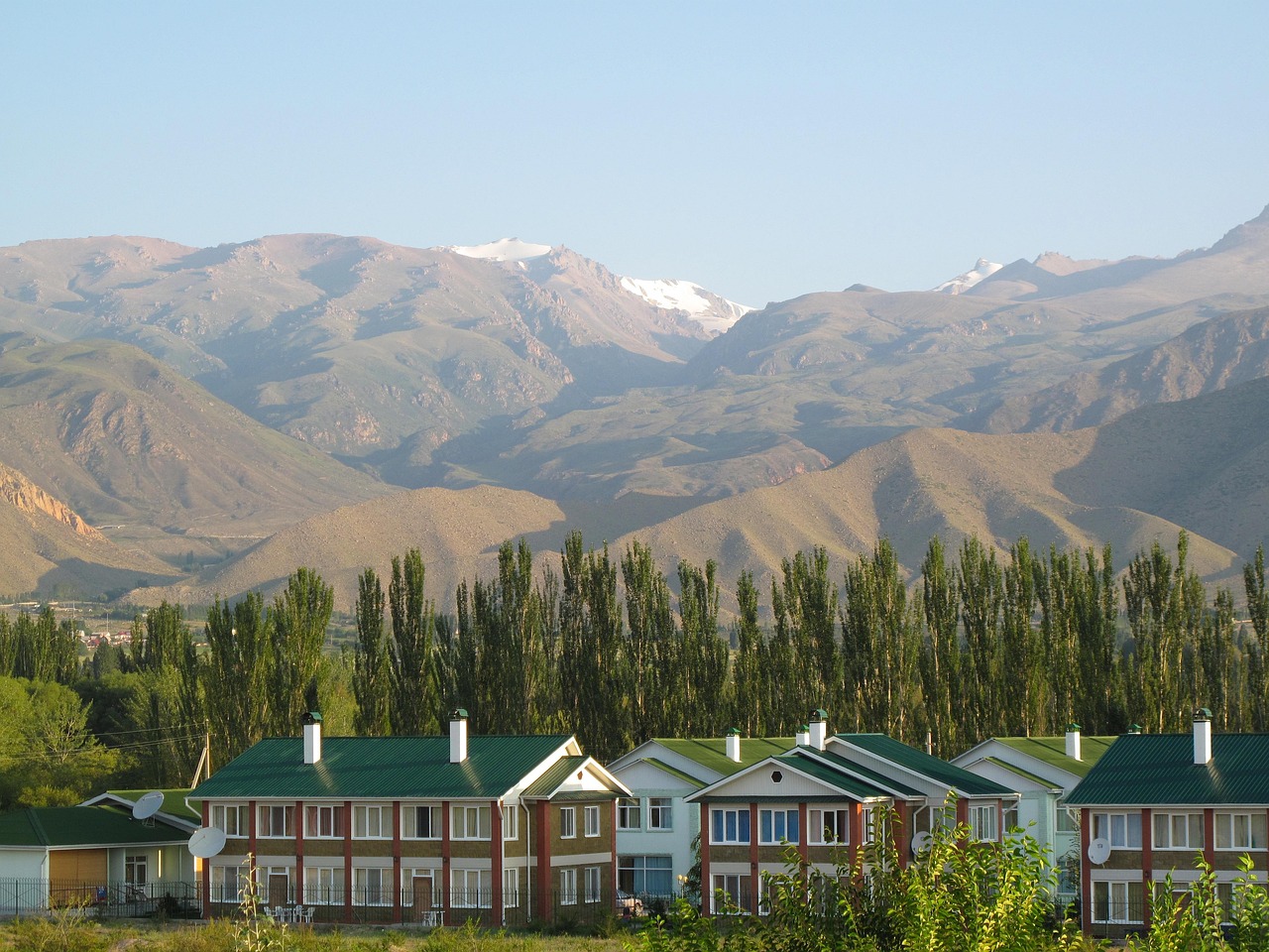 A traditional Kyrgyz village of green-roofed houses beneath the mountains