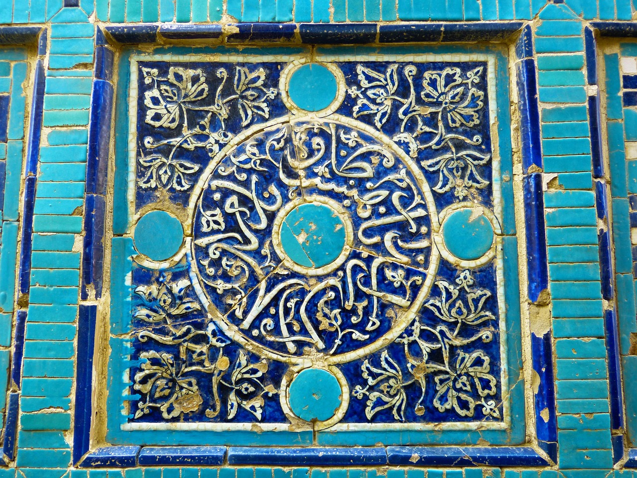 A close-up of blue and gold Islamic tilework with flowing calligraphy