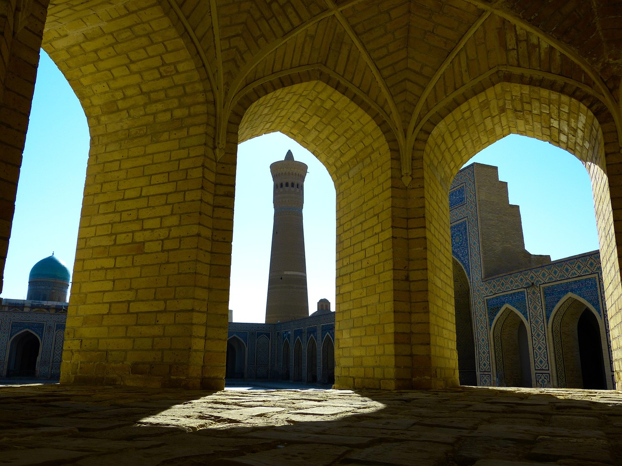 The Kalyan Minaret framed by the brick arches of the Kalyan Mosque courtyard in Bukhara