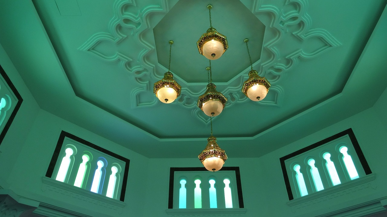 The green ceiling and hanging lamps inside a Malaysian mosque prayer hall