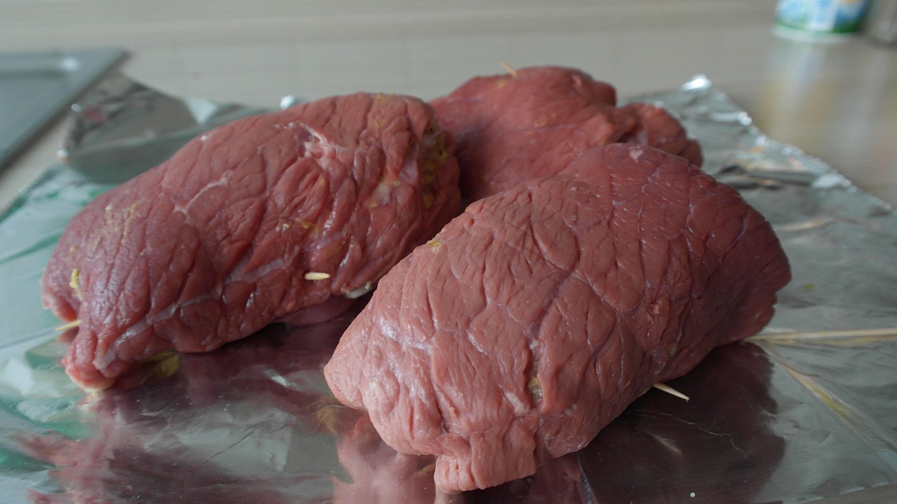 Beef roulades stuffed and rolled, showing the tight cylinder shape and twine work that keeps the filling inside during braising.