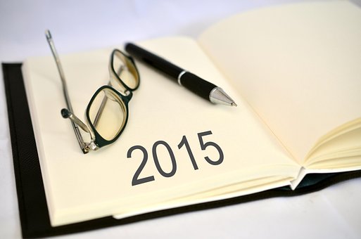 The year 2015 written in a book with glasses and a pen to signify top 100 companies for remote jobs