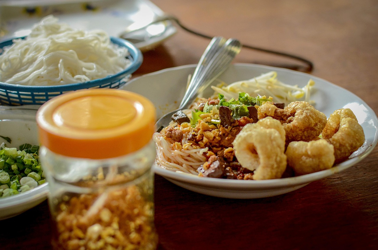 Thai food dish featuring rice topped with meat and vegetables, garnished with fresh herbs.