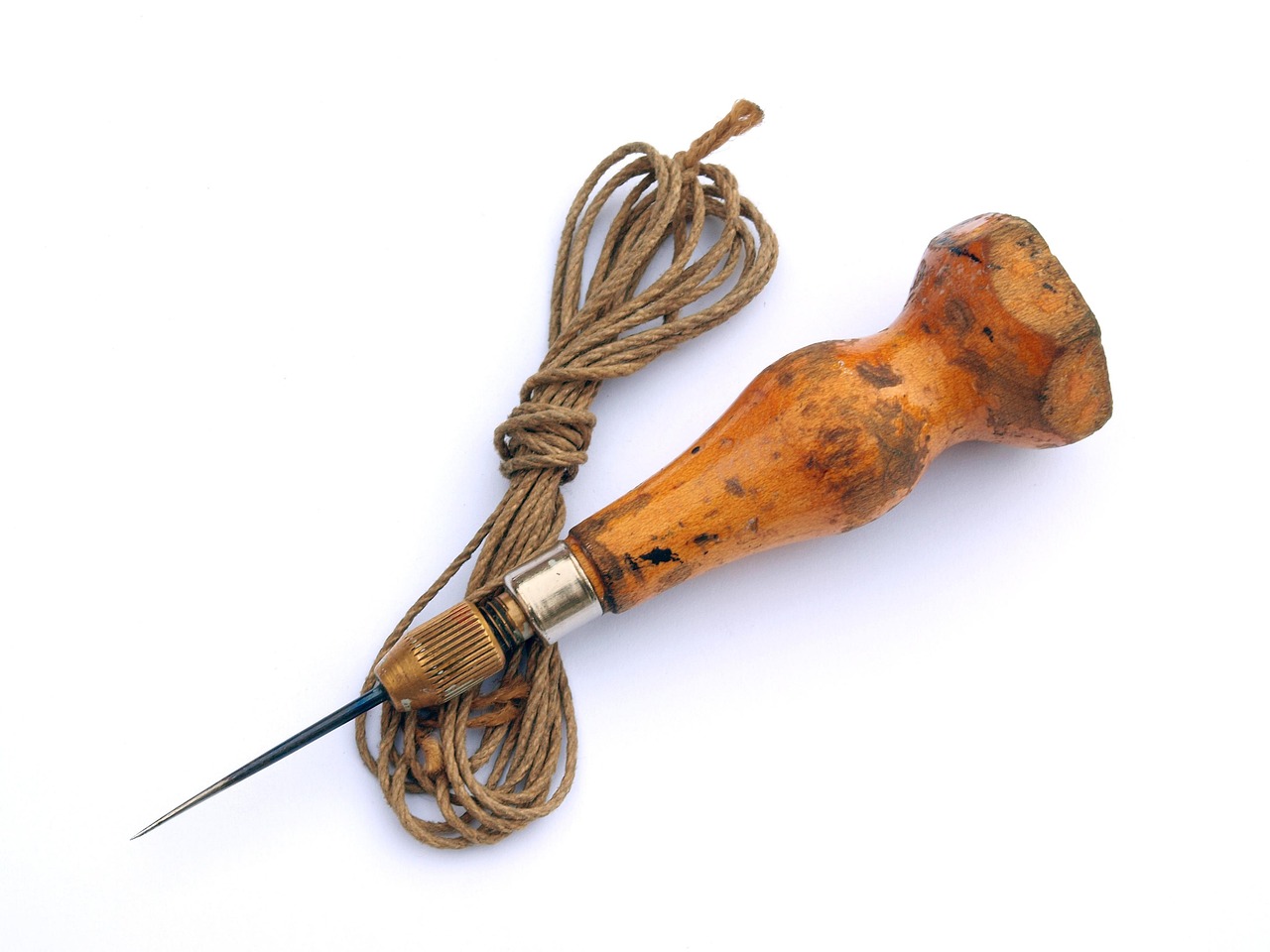 Leather awl tool resting beside coiled cord on a wooden surface.