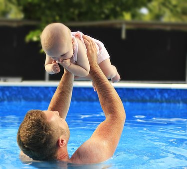 Rehabilitación de todo tipo de piscinas, revestimientos e impermeabilizaciones. Microcementos, suelos decorativos y en 3D, Renovación de hormigones y mucho más FERMA Piscinas y Microcementos en Toledo, Hombre con niño en los brazos en una piscina