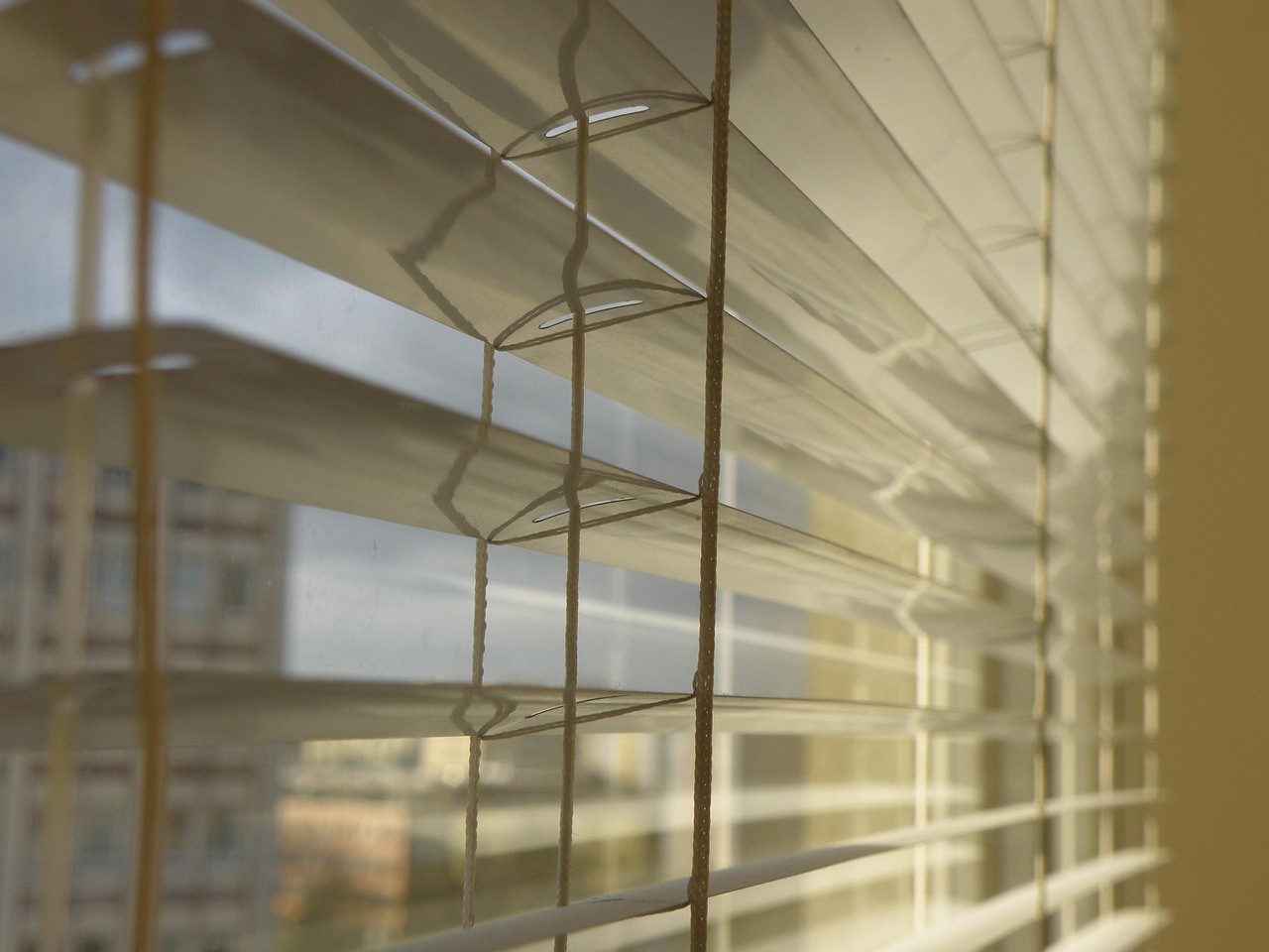 Close-up of horizontal venetian blind slats casting parallel shadow lines.