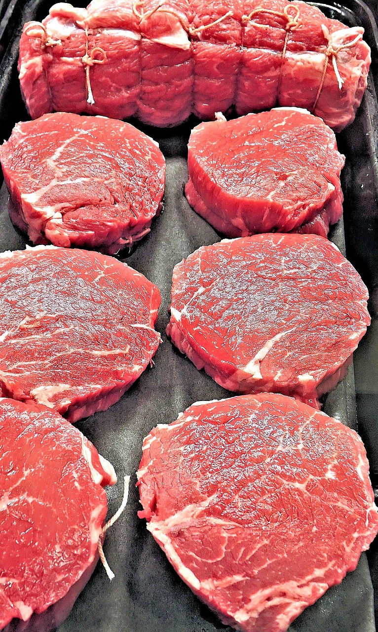 Raw ribeye steaks showing thick marbling and separated cap muscle on a butcher's counter