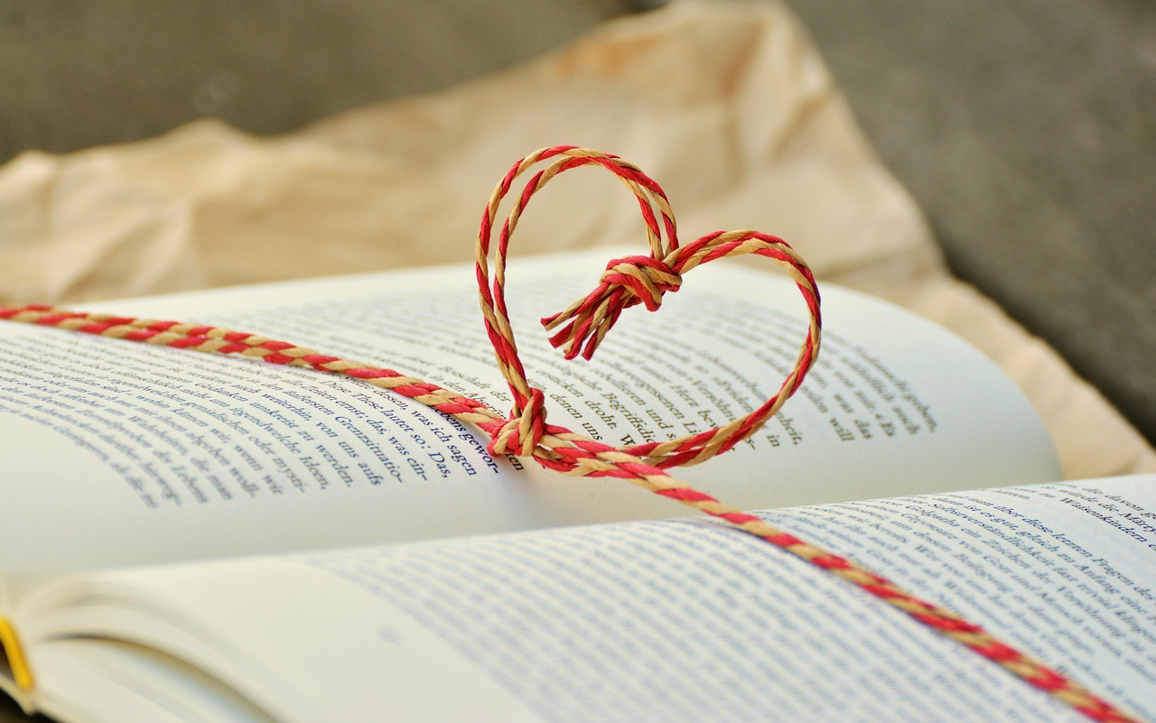Open book with a small red heart resting on its pages.