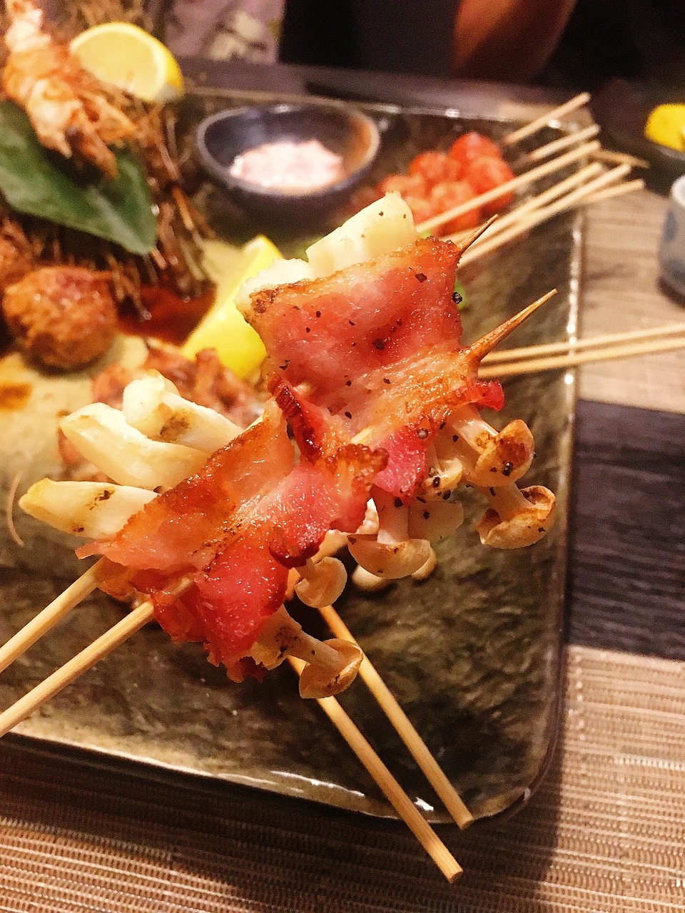 Japanese yakitori skewers on a plate with sliced negi green onion and a small dish of tare sauce