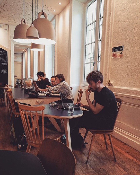 A young man browsing the internet on his laptop in a café.