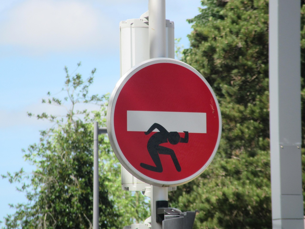Do not enter sign, but a stick figure is struggling under the weight of it