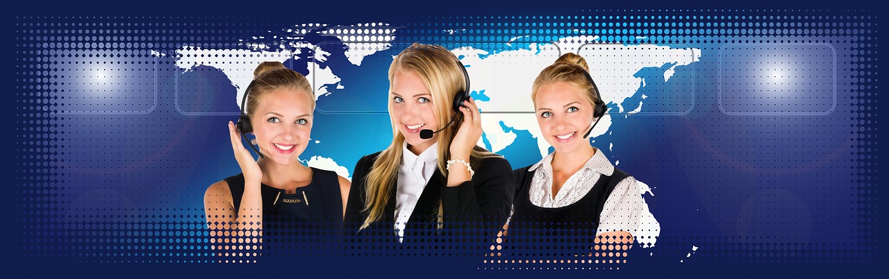 A woman wearing a headset working at a call center desk.