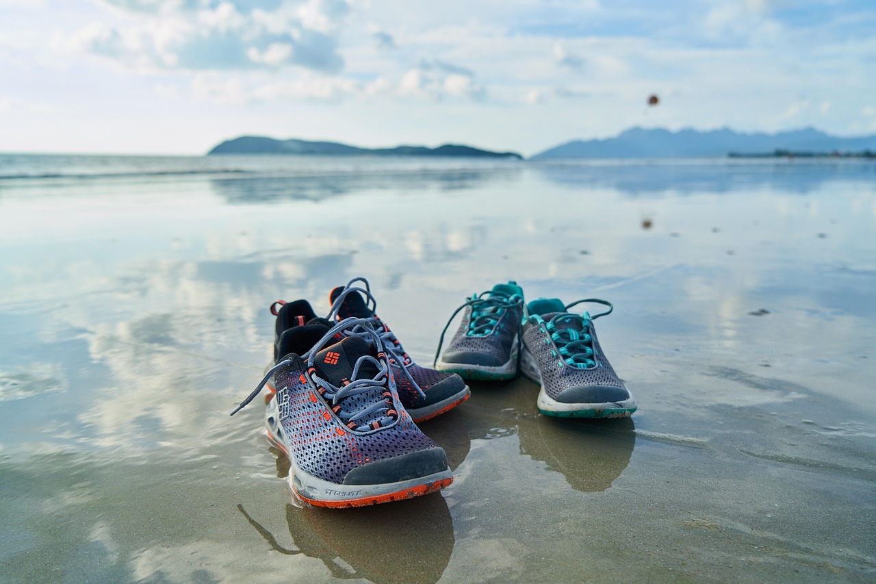 Zwei Paar Laufschuhe am nassen Strand bei bewölktem Himmel