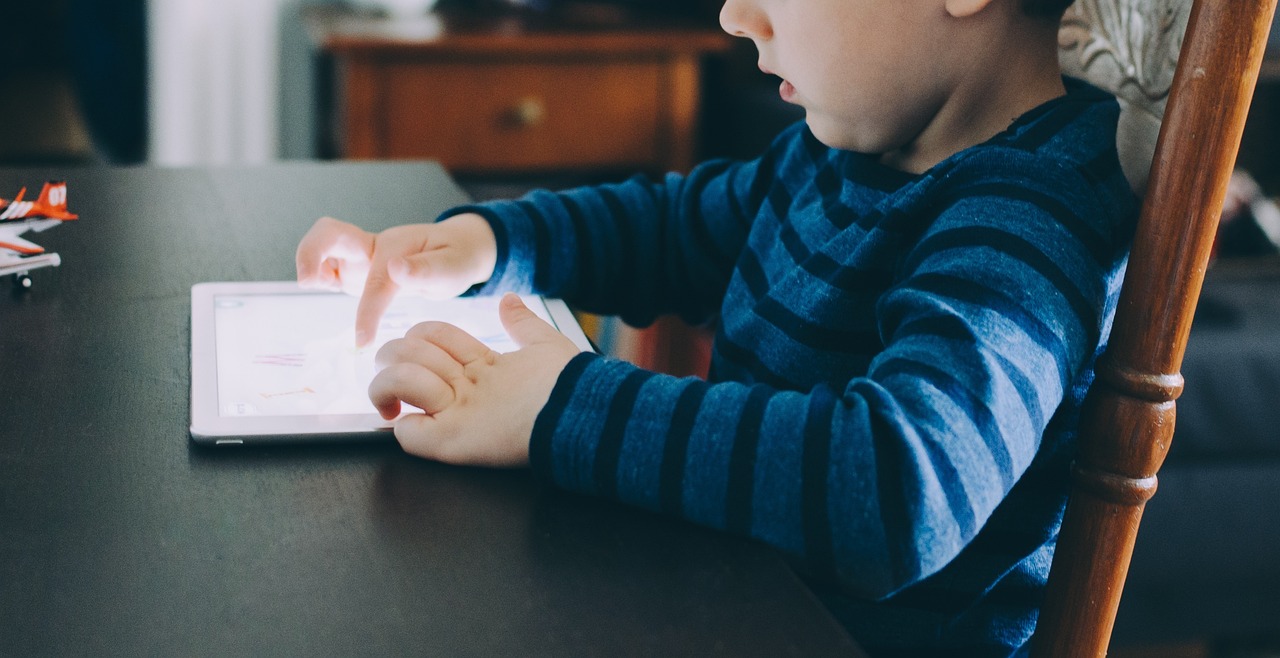 A child using an AI-based learning tablet with a teacher nearby, illustrating responsible use of artificial intelligence in childhood education in 2026.

 
