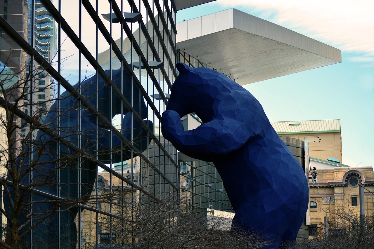 Large blue bear sculpture viewed through a glass building facade