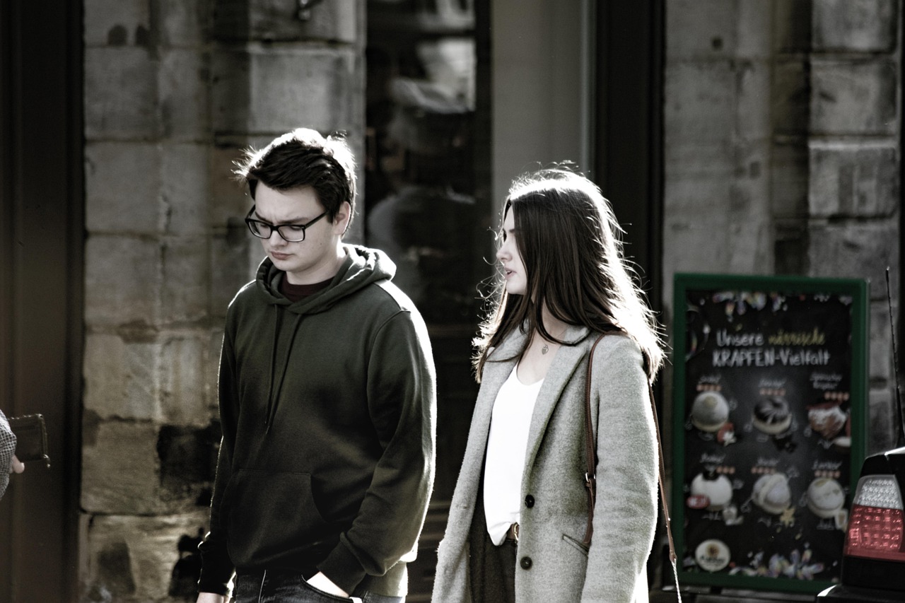 Two people facing each other in a tense conversation, one raising a hand in a gesturing motion.