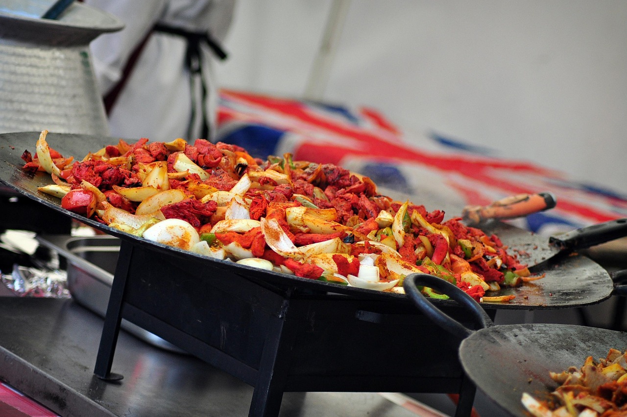 Tandoori chicken and Indian curry with whole spices, dried red chilies, black peppercorns, and coriander seeds arranged around a metal tray