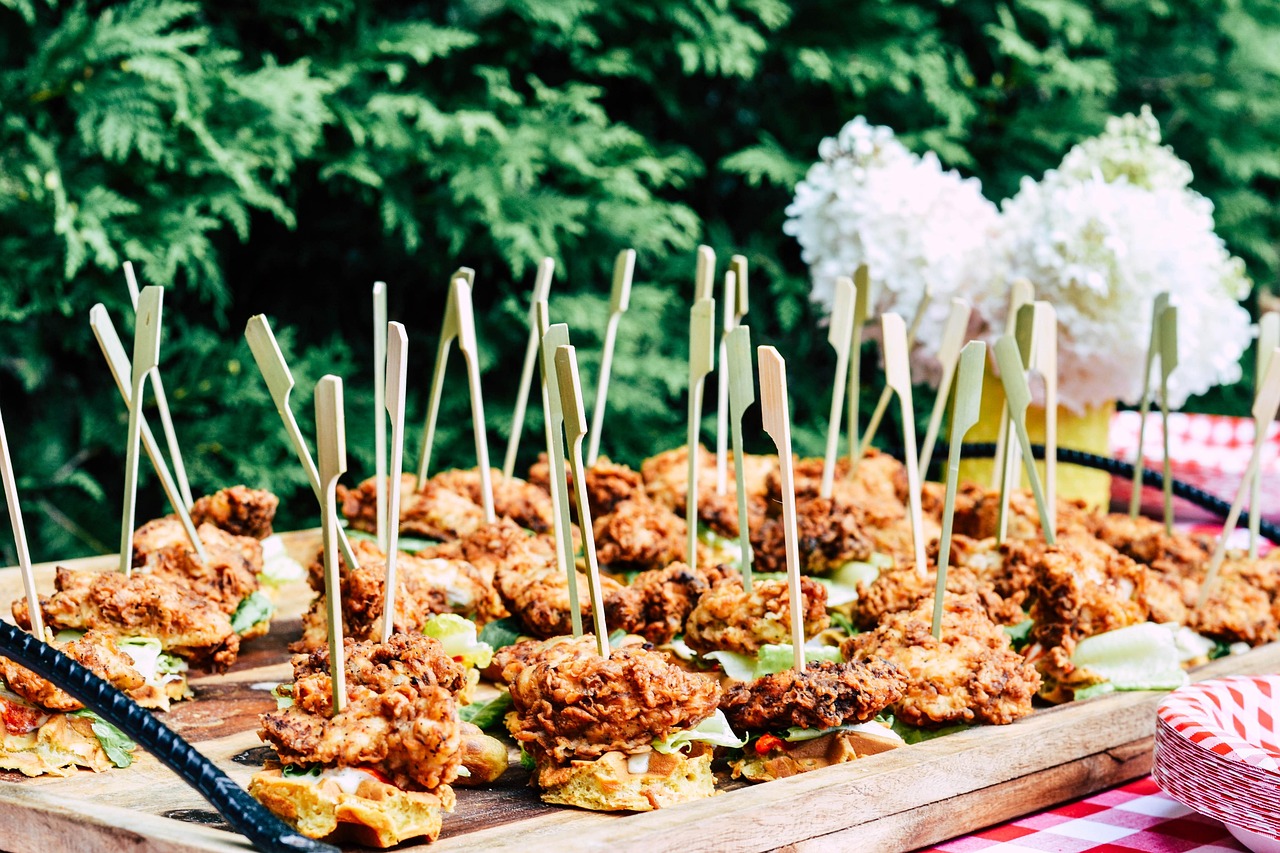 A plated Southern chicken and waffles: golden fried chicken thigh on a fluffy buttermilk waffle with syrup pooling in the squares.