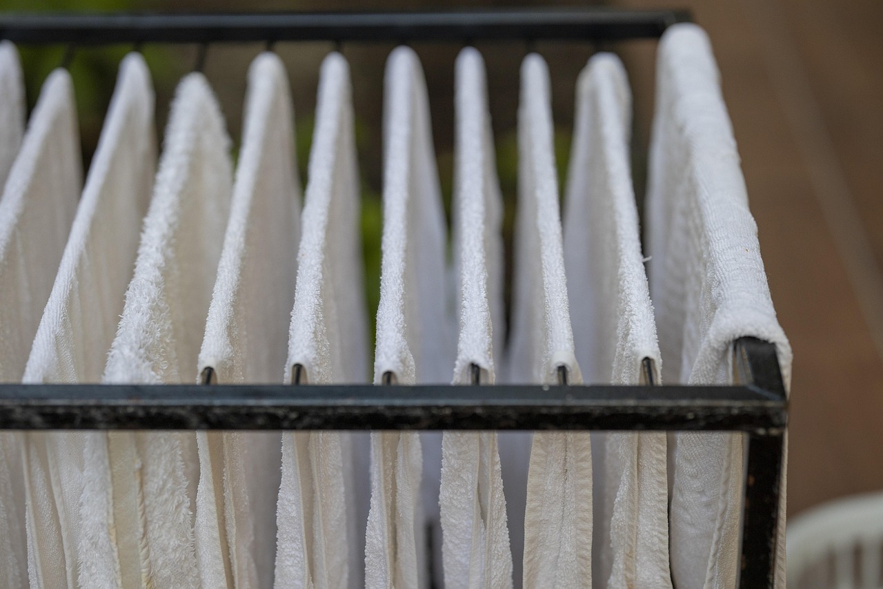 Folded white towels stacked on a shelf in a hotel bathroom