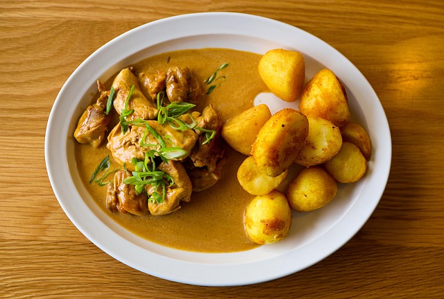 Boneless glazed chicken pieces plated with rice and steamed vegetables, coated in a dark sticky sauce