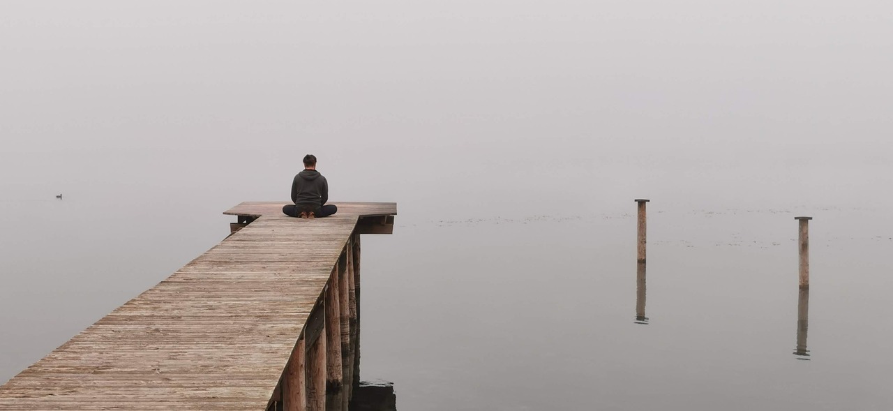 Person meditating by a calm lake