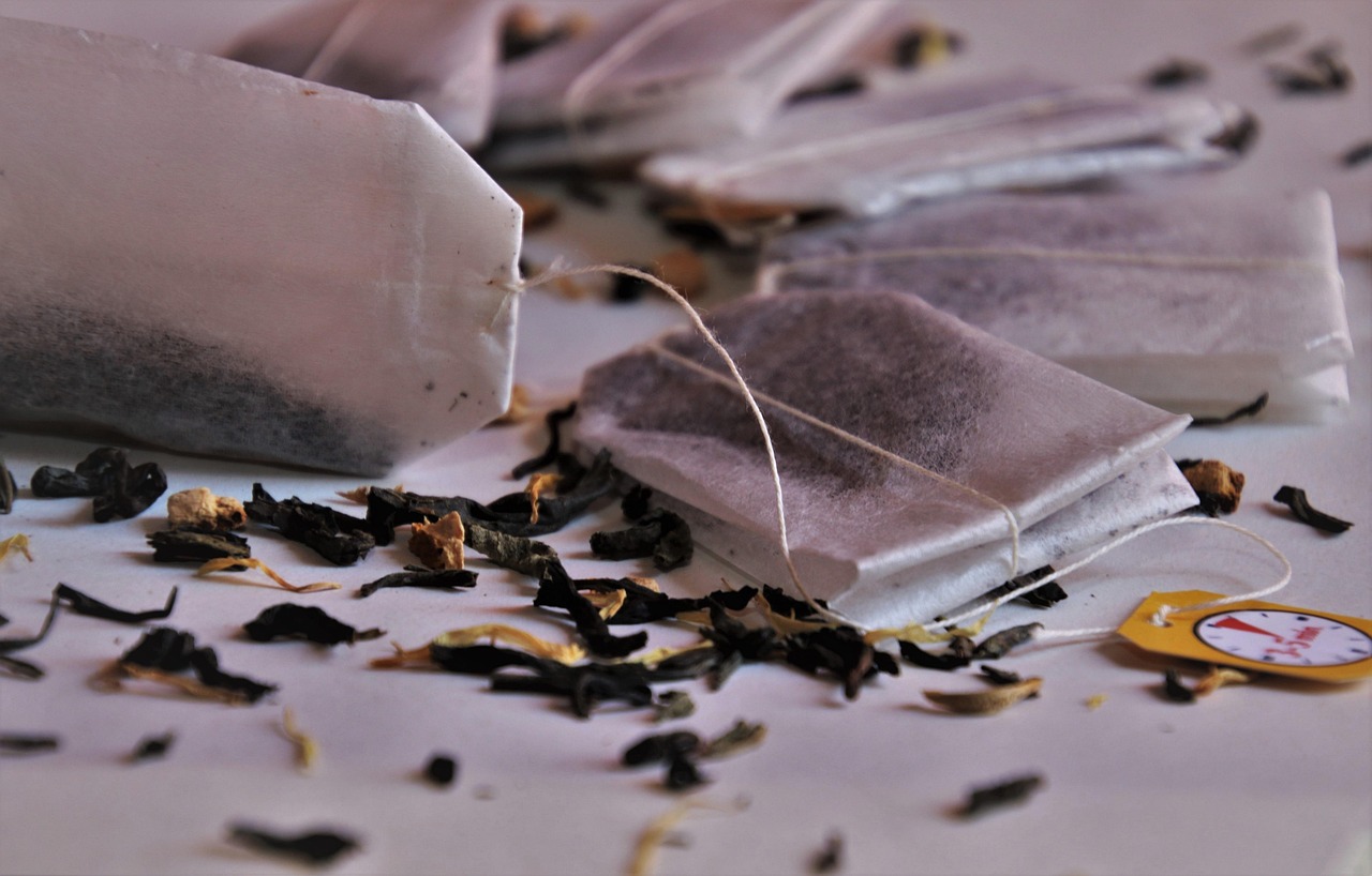 Loose leaf tea bags with dried tea leaves scattered on a light surface, representing the variety of tea formats that require correctly specified corrugated secondary packaging for wholesale and DTC shipping