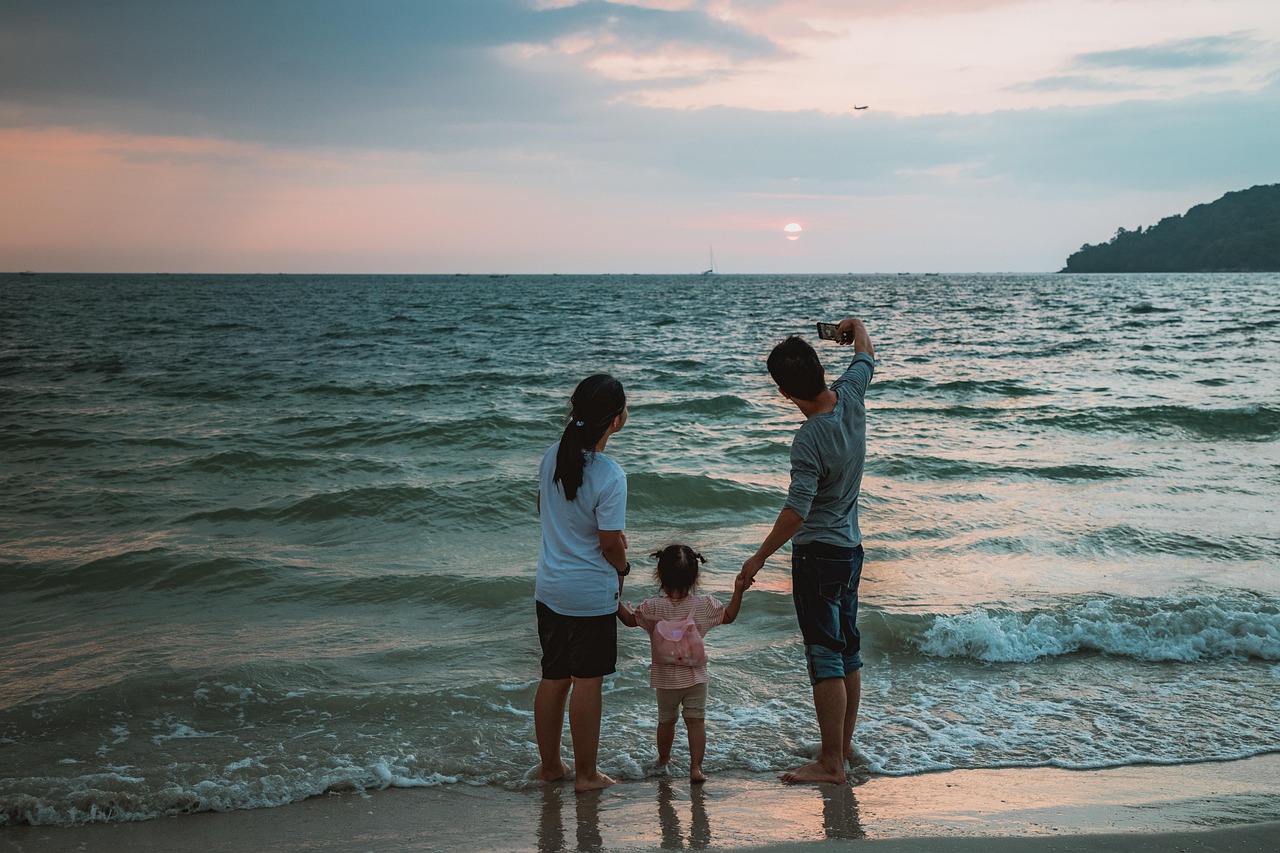 Family taking a selfie together on a sunny beach.