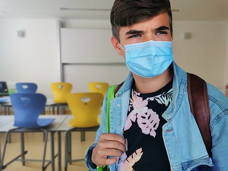 Pandemia w Polsce i szkolne absurdy, czyli nagana za katar Uczeń w maseczce na tle pustych ławek w szkole.