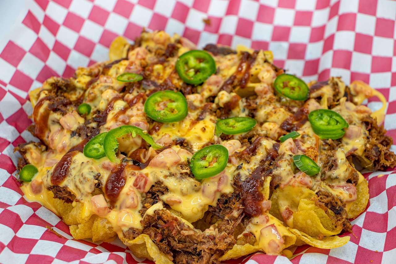 Sheet pan of loaded beef nachos topped with melted cheese, jalapeños, tomatoes and cilantro