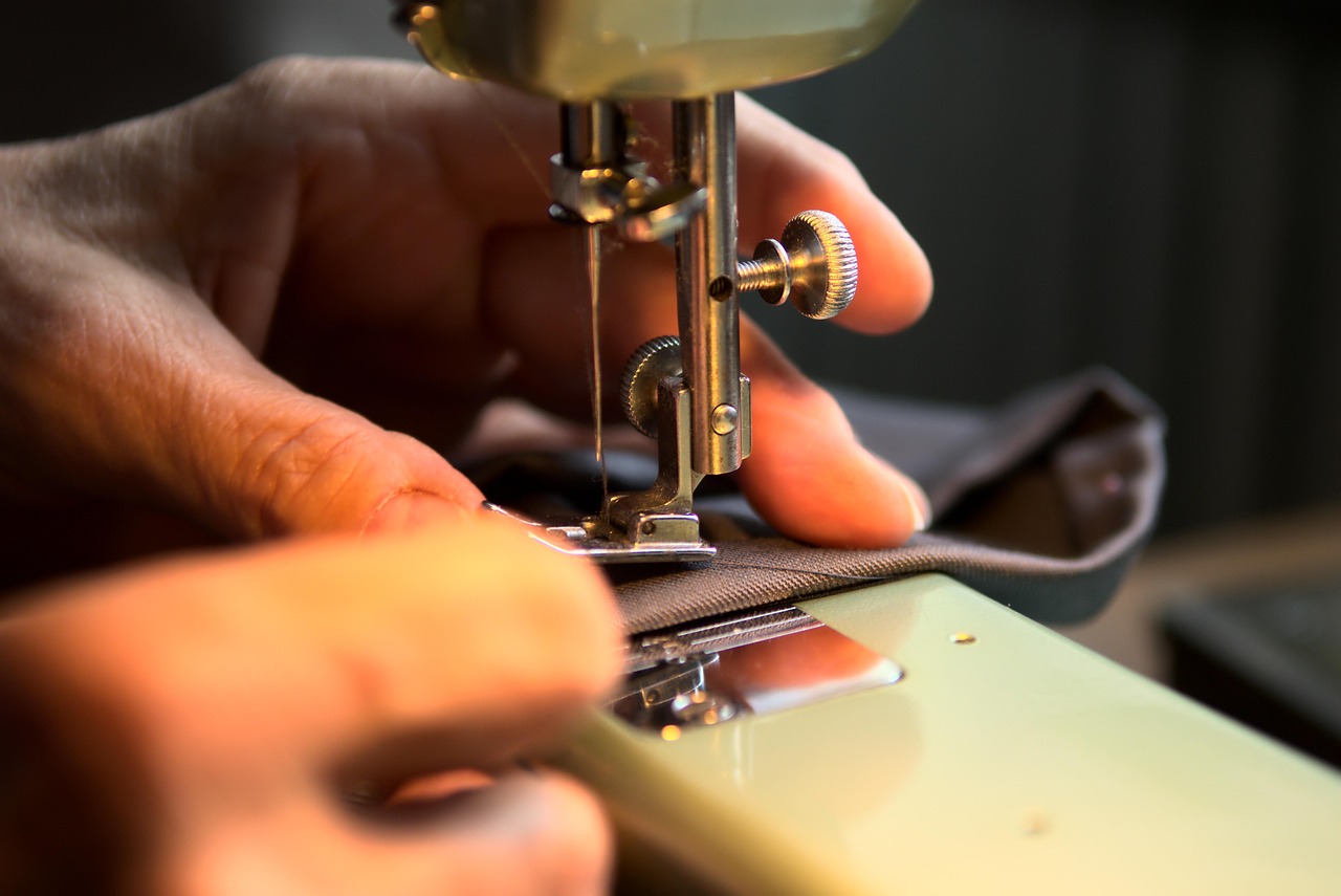 Hands guiding fabric through a sewing machine, garment craftsmanship