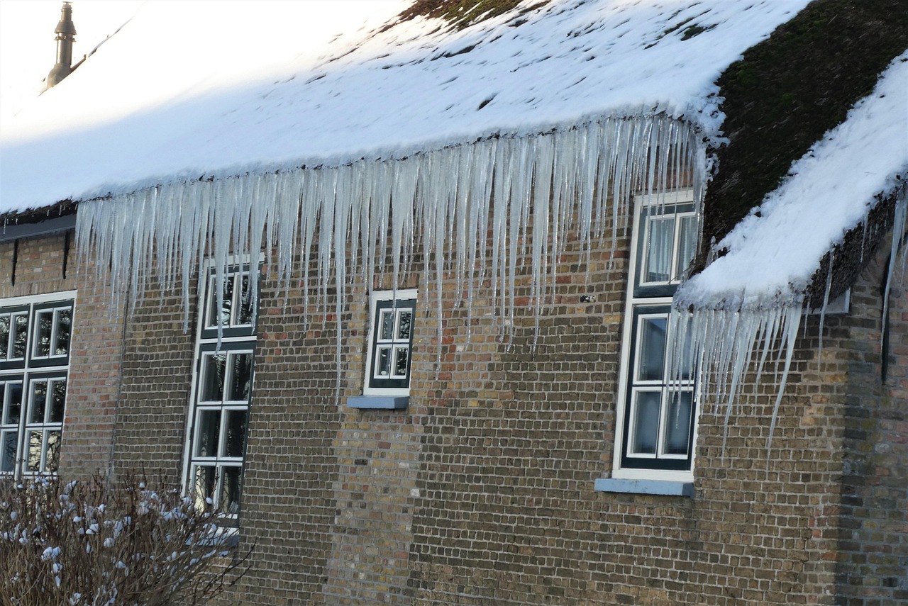 Icicles on a brick home signaling freeze conditions and ice dams
