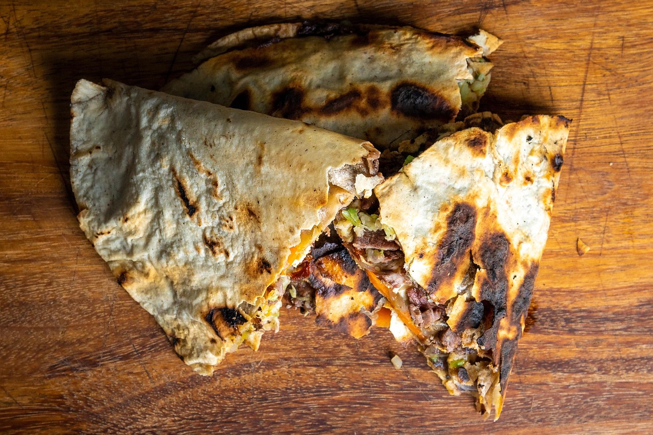 Beef and cheese quesadilla wedge showing melted cheese pull with fresh herbs