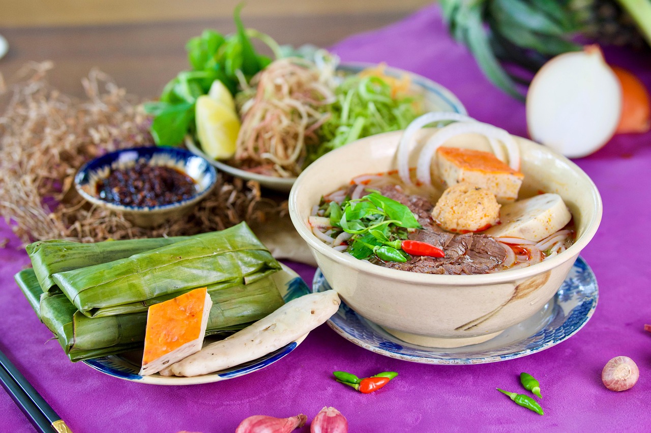 Bowl of Vietnamese beef pho with thin slices of rare beef, rice noodles, scallions and herbs in a steaming clear broth.