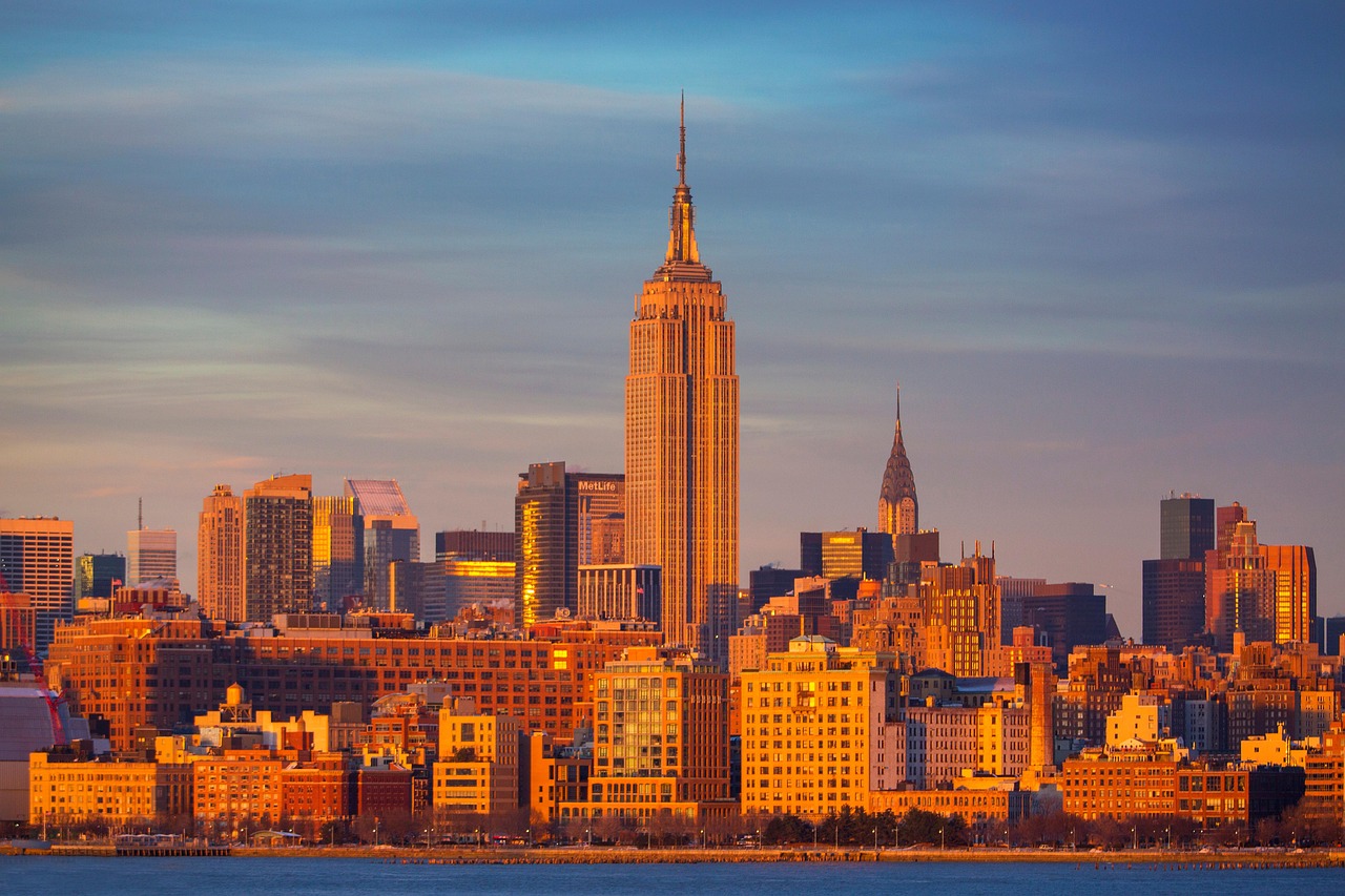 Empire State Building rising above surrounding Manhattan skyscrapers at dusk.