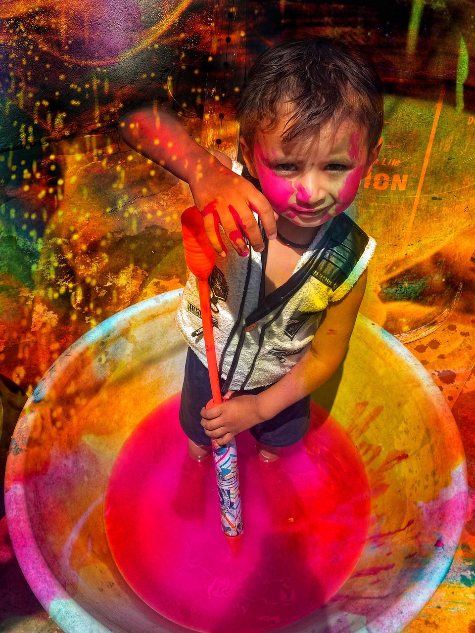 Joyful crowd throwing bright pink and yellow Holi colour powder during the festival of colours in India