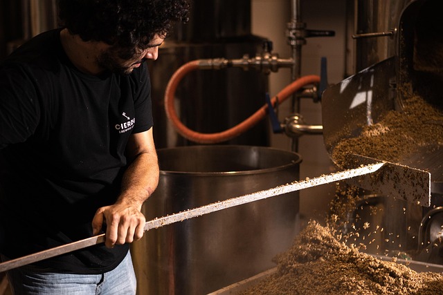 Brewer working beside craft beer brewing equipment
