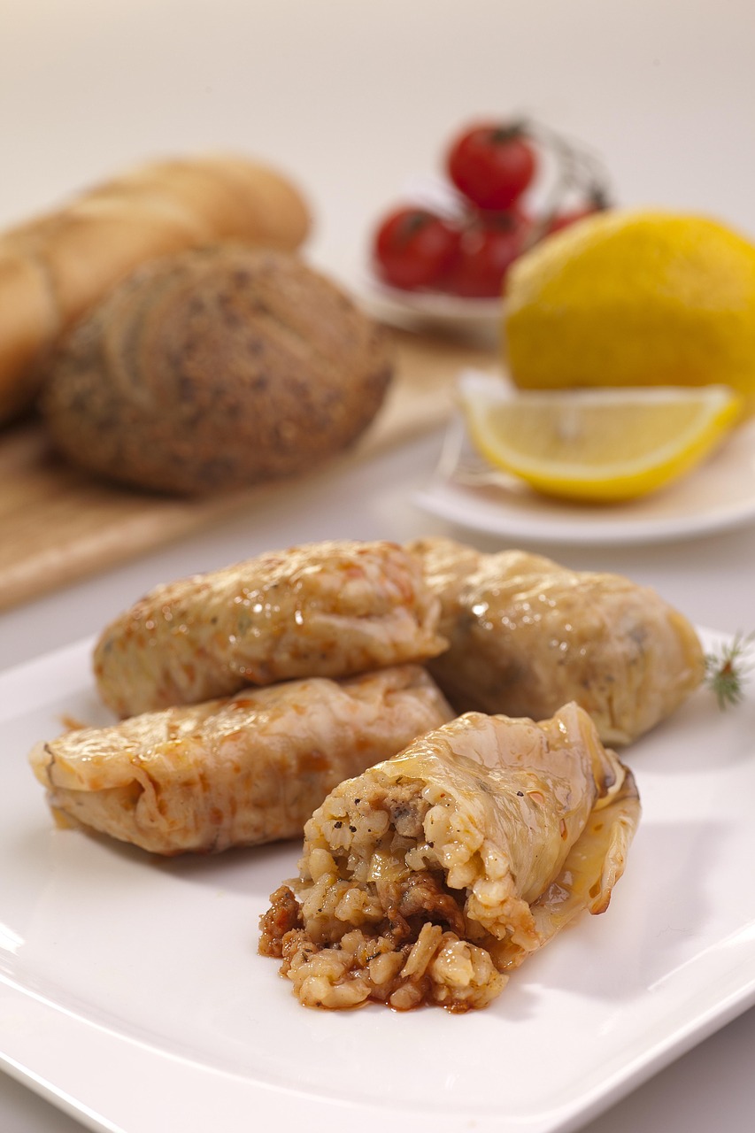 Cabbage rolls cut open to reveal the ground meat and rice filling, served with bread and lemon
