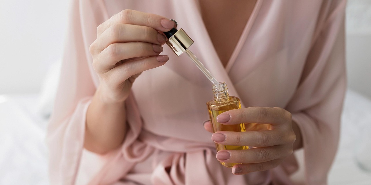 Woman examining her clear, even-toned skin in a mirror — the result of a consistent brightening serum routine using niacinamide or vitamin C
