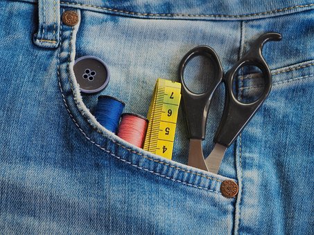 Gros plan sur du tissu recyclé et des outils de couture durables : fil, mètre ruban et ciseaux