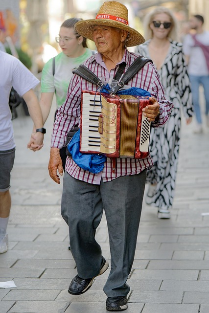 man, busker, accordion, elderly, casual, hat, walking, pavement, street, musician