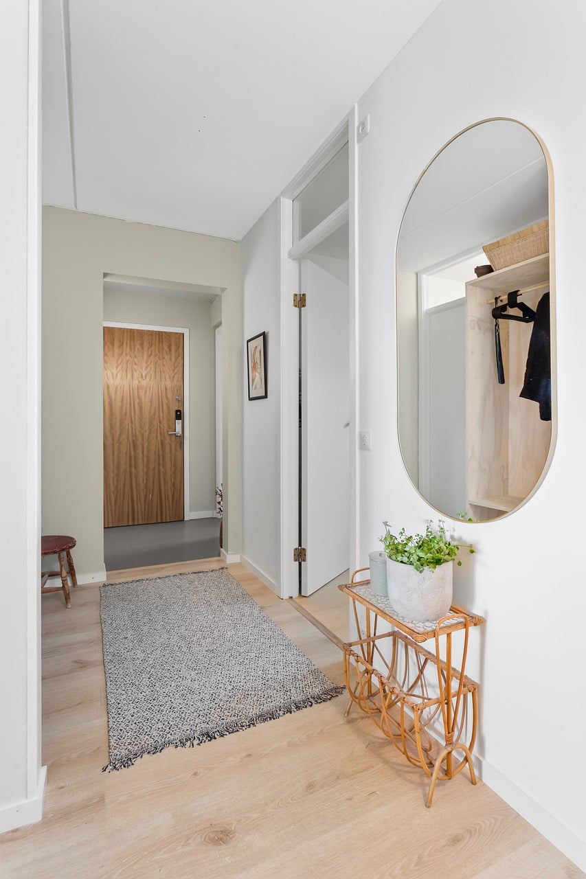 Large hallway mirror reflecting light in a narrow entryway space