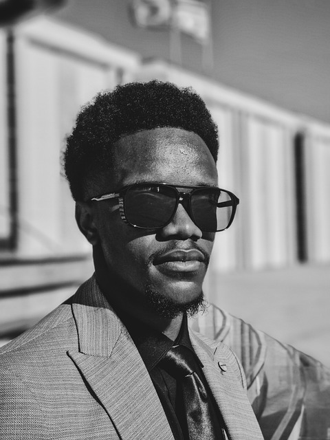 fashion, black man, glasses, minimalism, style, suit, mystery, mood, editorial, close up, contrast, confident, tension, eye contact, stare, soft focus, emotional portrait, depth, vulnerability, fashion model, thoughtful gaze, cinematic look, artistic lighting, slow moment, inner world