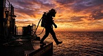 Random: commercial diver, diving suit, helmet, oxygen tank, equipment, diving platform, boat deck, vessel, silhouette, nature, sunset, dramatic sky, crimson clouds, sea, ocean, water droplets, marine engineering, hazardous work, industrial, adventure